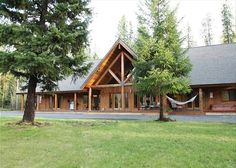 a large wooden house sitting on top of a lush green field next to a forest