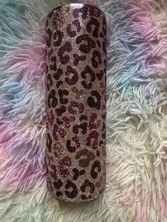 a pink and brown leopard print glitter tumbler on a white fur covered surface with the lid open