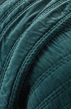 a close up view of a green comforter on a bed with blue sheets and pillows