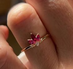 a woman's hand with a ring on it that has a flower shaped diamond in the middle