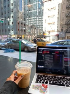 a laptop computer sitting on top of a table next to a cup of coffee and a drink