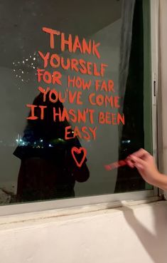 a person sitting in front of a window with writing on the window sill that says, thank yourself for how far you've come it hasn't been easy