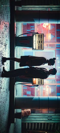 two people standing next to each other in front of a building with neon lights on it