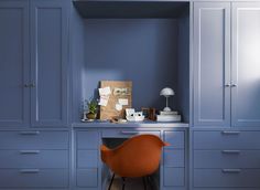 an orange chair sitting in front of a desk with a lamp on top of it