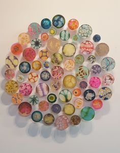 a bunch of different types of marbles on a white surface with one being surrounded by smaller ones