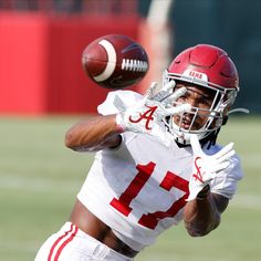 a football player catching a ball in the air with one hand and his other arm out