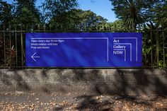 a large blue sign on the side of a road with trees in the back ground