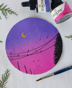 a purple and pink painting with some paintbrushes on the table next to it