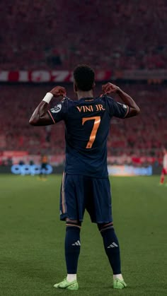 a man standing on top of a soccer field holding his hands behind his back as if he is ready to kick the ball