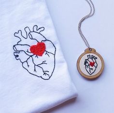 an embroidered heart on a white t - shirt next to a small wooden charm necklace