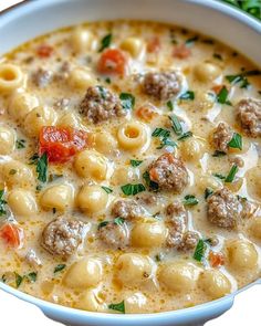 a close up of a bowl of soup with meatballs and cheese in it on a table