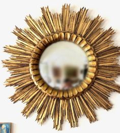 a gold sunburst mirror hanging on the wall next to a blue and white painting