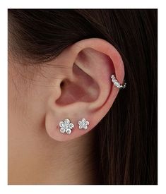 a woman wearing three flower shaped ear piercings on her left and right side of the ear