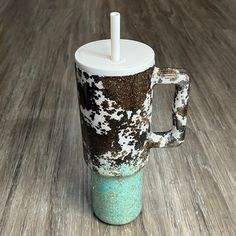 a coffee cup with a straw sticking out of it's lid sitting on a wooden floor