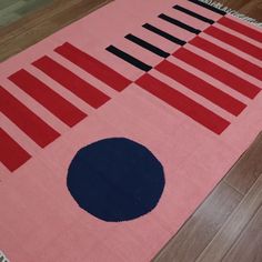 a pink rug with black and blue circles on it in the middle of a wooden floor