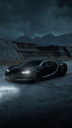 a black bugatti car parked in front of an ancient structure at night with lights on