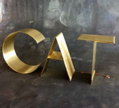 the letters eat are made out of gold metal and sit on a black table top