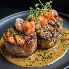 two pieces of meat on a plate with sauce and garnish