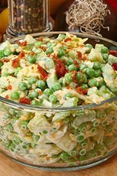 a bowl filled with pasta and peas on top of a wooden table next to other food items