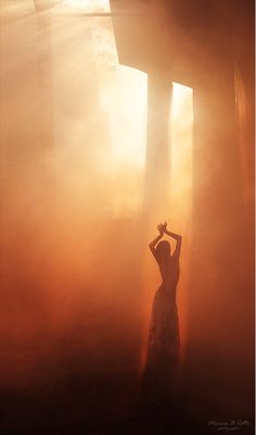 a woman standing in front of a cross on a foggy day with her hands up