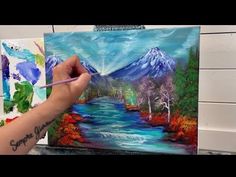 someone is painting a mountain scene with water and trees