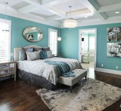 a bedroom with teal walls and white bedding in the center, along with a mirror on the wall