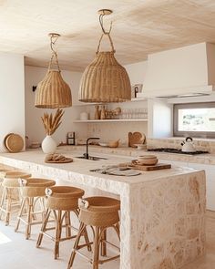 an island with stools and baskets on it in the middle of a large kitchen