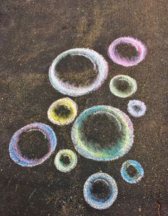 colored circles are arranged in the shape of a circle on asphalt with chalk crayons