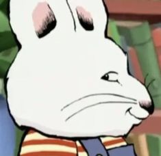 a white rabbit wearing a striped shirt in front of bookshelves