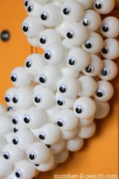 a bunch of white balls with black eyes hanging from the side of a yellow door