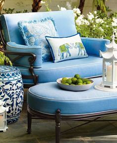 a blue and white couch sitting on top of a patio next to a table filled with fruit