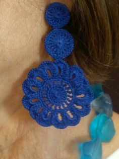 a woman wearing blue crochet earrings on her neck