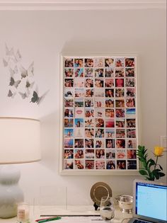 a laptop computer sitting on top of a desk next to a lamp and pictures hanging on the wall