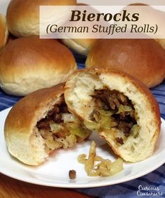 some bread rolls on a white plate with one cut in half