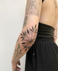 a woman's arm with tattoos on it and flowers in the middle of her arm