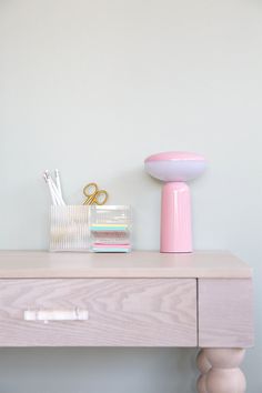 a desk with a pink lamp and other items on it