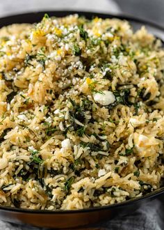 a bowl filled with rice and herbs on top of a tablecloth next to a fork