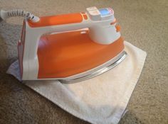 an orange and white iron sitting on top of a towel