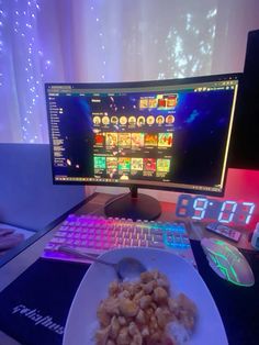 a computer monitor sitting on top of a desk next to a white plate with food