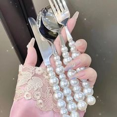 a woman holding a fork and knife with pearls on it