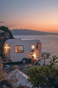 an rv parked on the shore at dusk with its lights on and it's door open