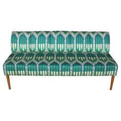 a green and white patterned couch with wooden legs