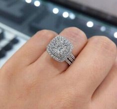 a woman's hand with a diamond ring on top of her finger and a keyboard in the background