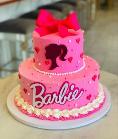 a pink cake with a bow and name on the top that says barbie is decorated