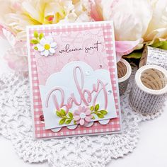 a pink and white card with the word baby on it, next to some flowers