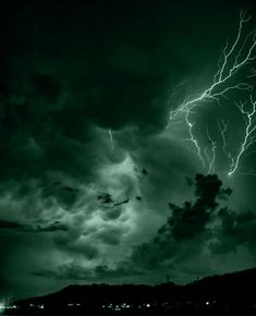 a black and white photo of a lightning storm in the night sky with dark clouds