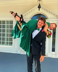 a man carrying a woman on his back in front of a house with white trim