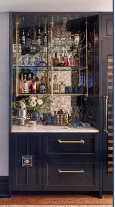 a bar with lots of bottles and glasses on the shelves in front of it's doors