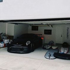 two cars are parked in the garage with their doors open and one car is upside down