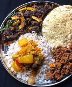 a metal plate topped with rice, meat and veggies